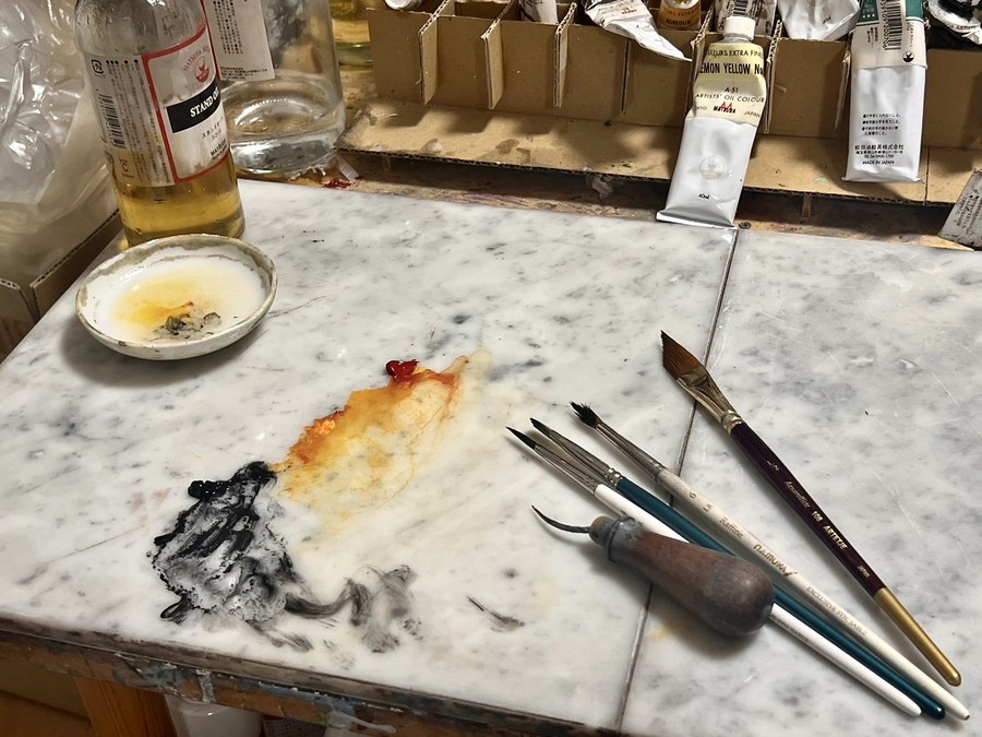 大理石のパレットに並ぶ絵の具、筆、パレットナイフ、チューブ